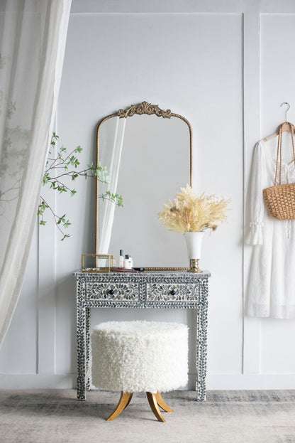 Arched gold mirror with ornate top detail close up