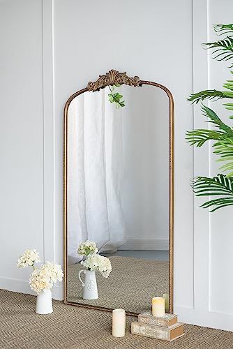Gold arched mirror leaning against wall in bedroom full body reflection