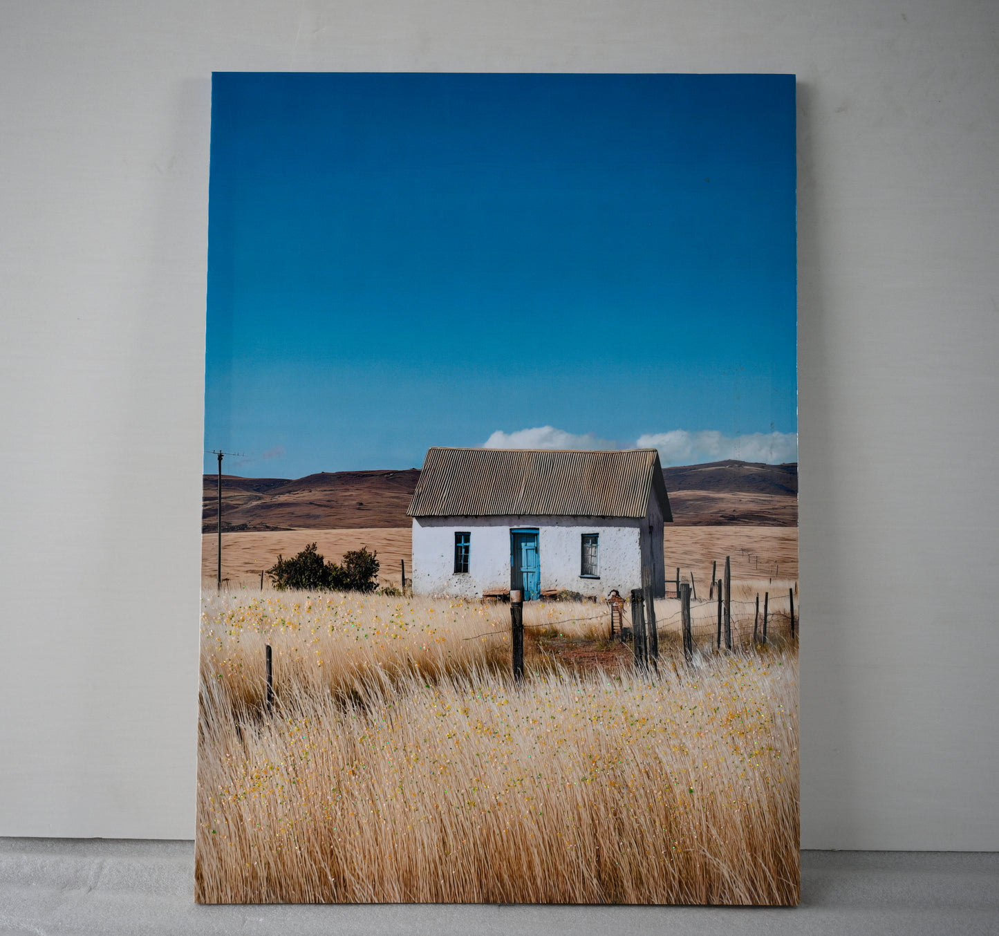 Close-up of farmhouse canvas wall art showing white cottage and wildflowers