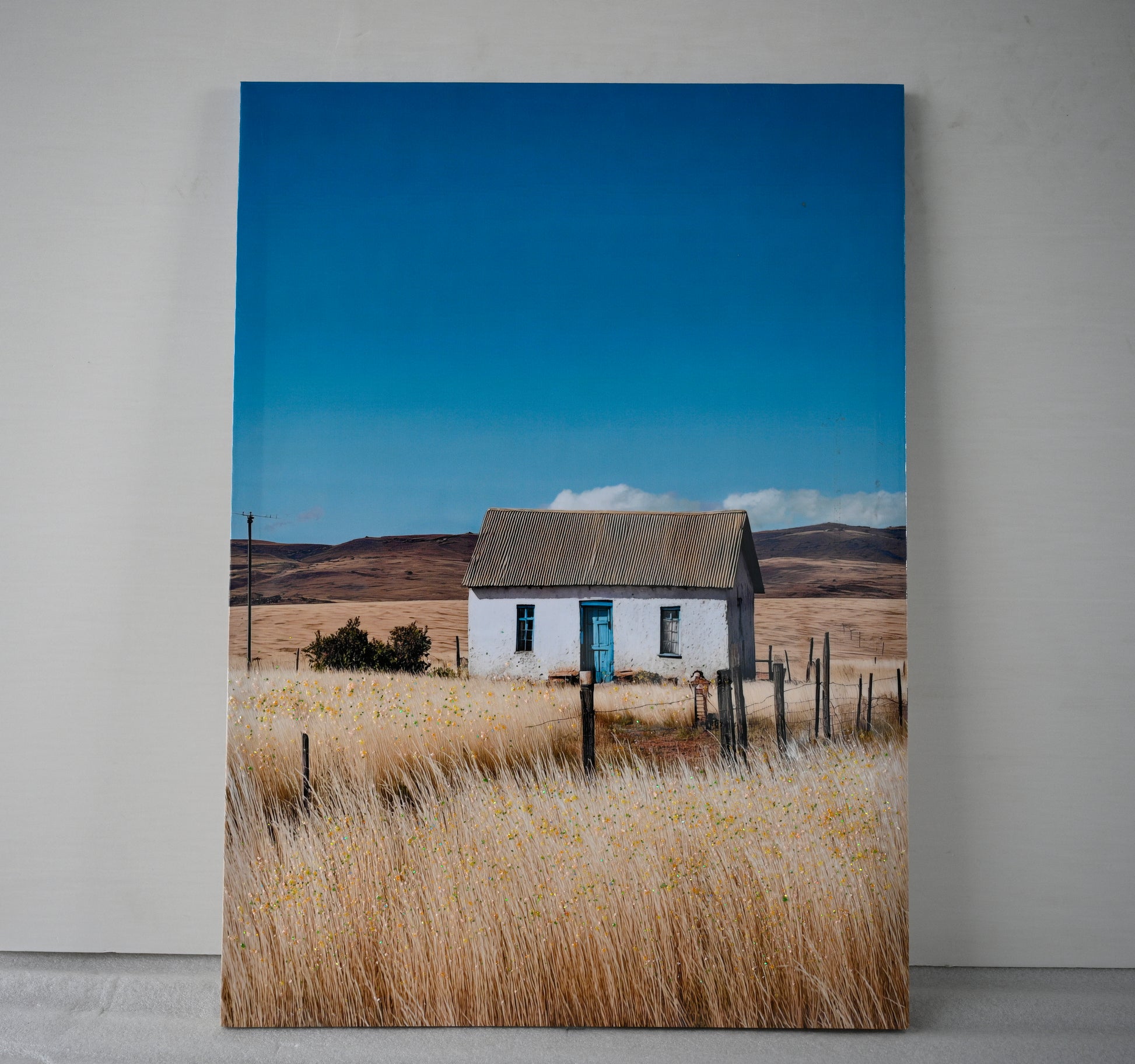 Close-up of farmhouse canvas wall art showing white cottage and wildflowers